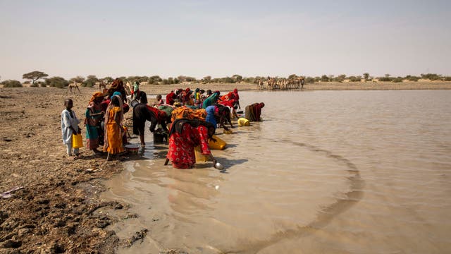 Eine Gruppe von Frauen und Kindern sammelt Wasser aus einem schlammigen Fluss im Tschad