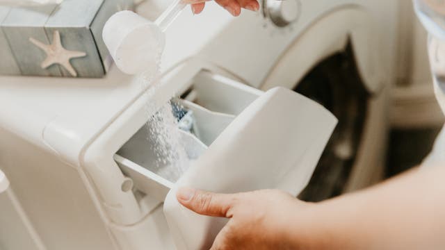 Waschpulver wird ins Waschmittelfach einer Waschmaschine gefüllt.