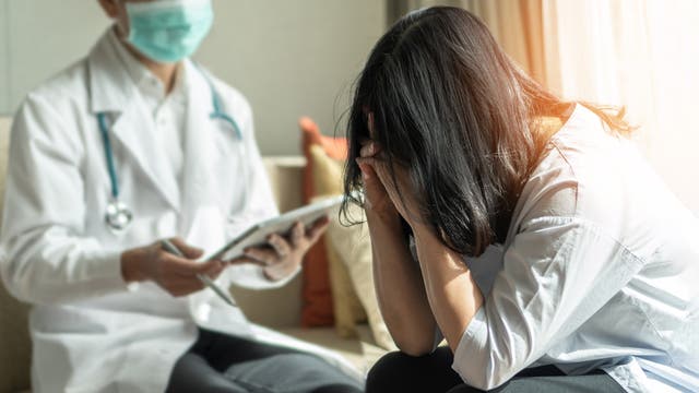 Frau stützt verzeifelt den Kopf in die Hände während eines Arztgesprächs