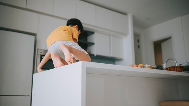 Junge klettert auf einer Küchenzeile herum