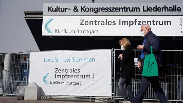 Ein älteres Paar geht an den Schildern des ZIZ Stuttgart vorbei.