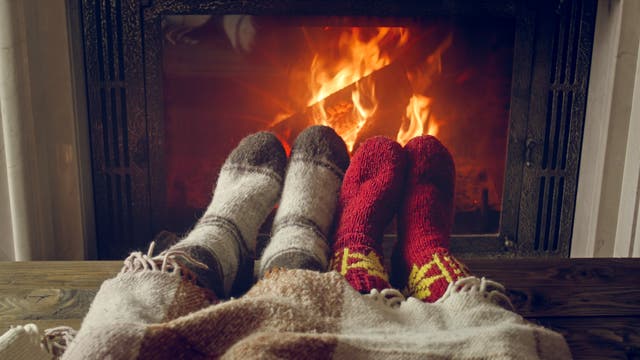 Zwei Paar Füße in Kuschelsocken wärmen sich am brennenden Kamin