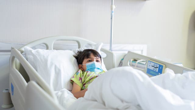 Ein kleines Kind mit MNS liegt in einem Krankenhausbett.
