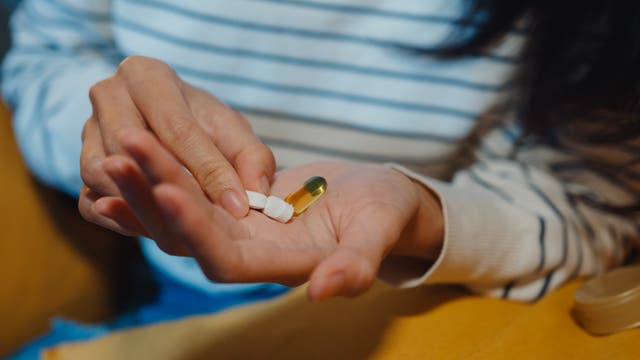 Eine Frau schüttet sich verschiedene Tabletten auf die Hand