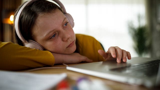 Ein Mädchen sitzt erschöpft vor dem Rechner
