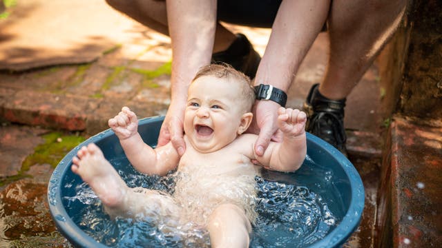 Ein Baby strampelt in einer Schüssel mit Wasser.