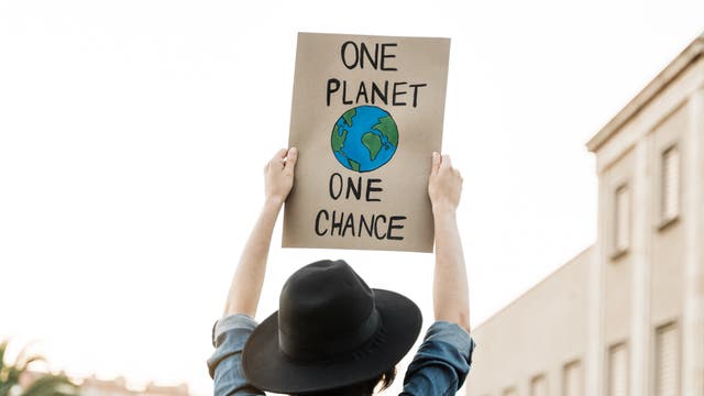 Ein Mann hält ein Plakat hoch mit »One Planet - one chance«