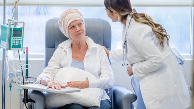 Eine Onkologin spricht mit eine Krebspatientin, die eine Chemotherapie erhält. Die Patientin hört aufmerksam zu.