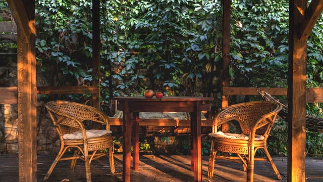 Zwei Stühle und ein Tisch aus Holz in einer gemütlichen Gartenlaube. 