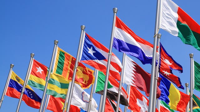 Diverse Nationalflaggen an eng stehenden Fahnenmasten.