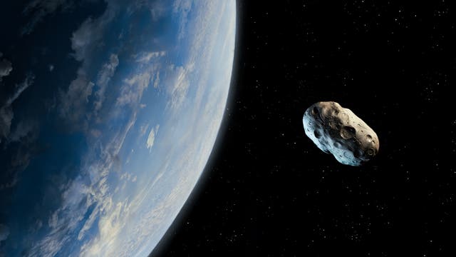 Ein Asteroid neben einem blauen, erdähnlichen Planeten.