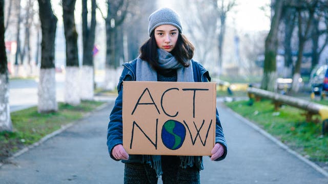 Junge Klimaaktivistin hält ein Schild mit der Aufschrift »Act Now« 