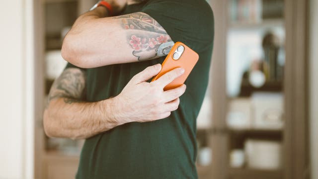 Mann hält sich ein Smartphone an den Oberarm, an welchem ein Sensor befestigt ist