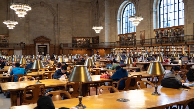 Blick in die New York Public Library mit in Bücher vertieften Menschen an Arbeitstischen