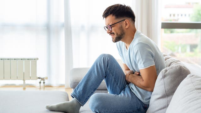 Mann hält sich den Bauch und krümmt sich vor Schmerzen
