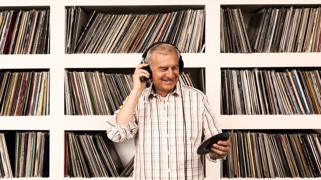 Ein Mann hört eine LP vor seiner Plattensammlung