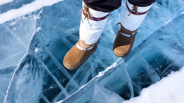 Nahaufnahme von traditionelle Mukluks, die eine Person trägt, die auf einer Eisfläche steht.