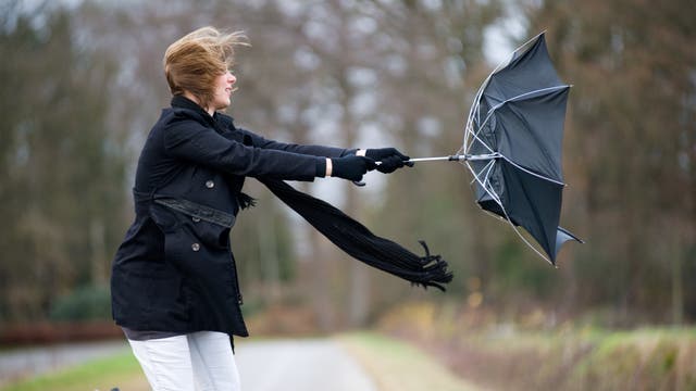 Frau kämpft mit umgeklapptem Regenschirm