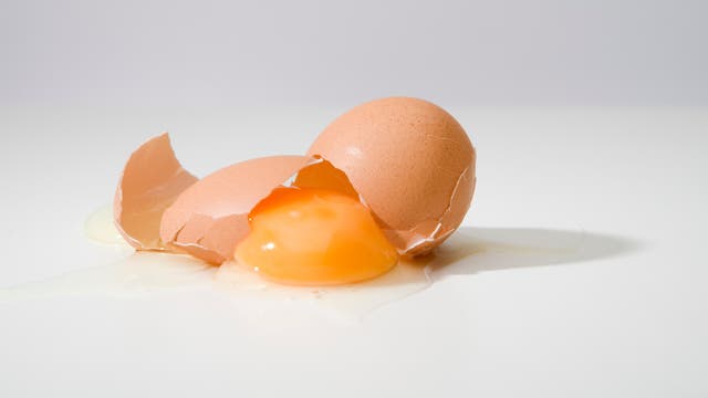 Ein zerbrochenes Ei auf einem weißen Tisch.