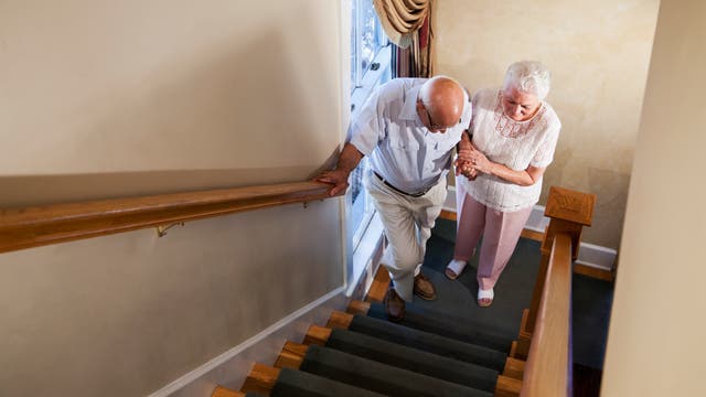 Eine ältere Dame hilft einem Mann die Treppe hinauf.