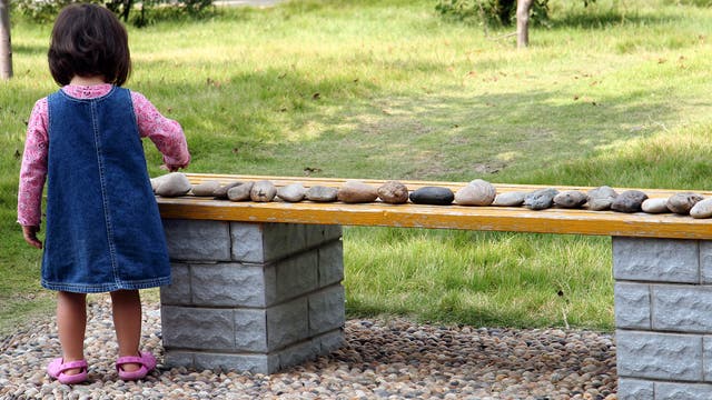 Kind ordnet Steine auf einer Bank der Reihe nach