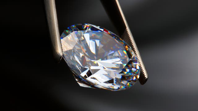 Ein geschliffener Diamant in einer Pinzette.