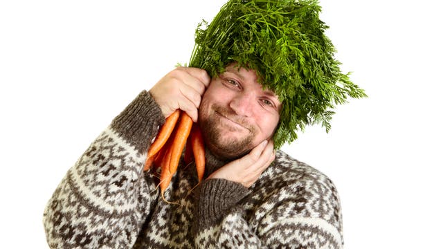 Ein diätaffiner Mann posiert mit Gemüse