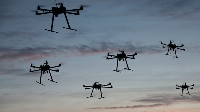 Mehrere Drohnen mit sechs Rotoren im Flug gegen den Himmel fotografiert. 
