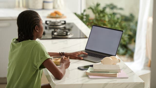 Mädchen frühstückt am Laptop