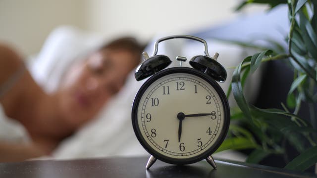Wecker am Bett zeigt die Uhrzeit: Viertel nach sechs