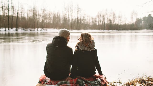 Junges Paar sitzt im Winter an einem See