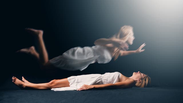 Frau schwebt über ihrem Körper