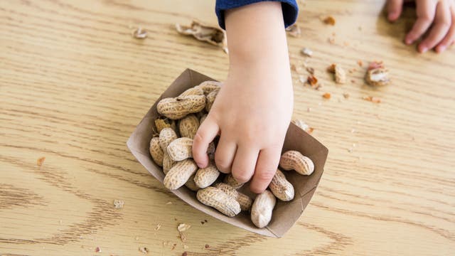 Kind greift nach Erdnüssen