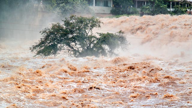 Schlammige Fluten toben durch die Straßen einer tropischen oder subtropischen Stadt.