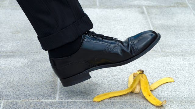 Der Fuß eines Mannes, der im Begriff ist, auf einen Bananenschale zu treten.