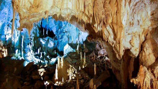 Eine hohe Tropfsteinhöhle spektakulär ausgeleuchtet.