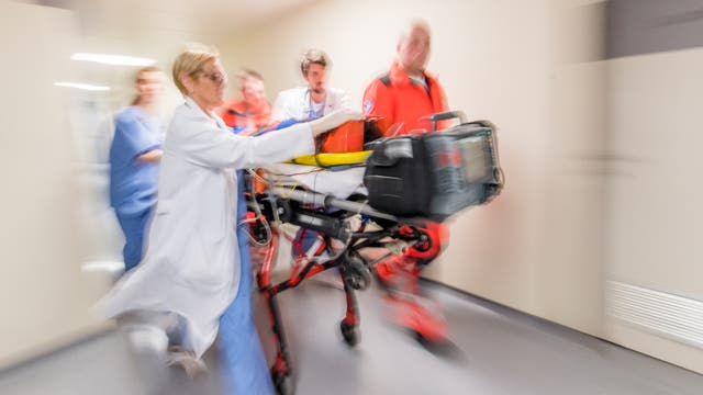 Einlieferung eines Notfalls im Krankenhaus. Notärzte und Krankenhauspersonal transportieren Verletzten auf einer mobilen Liege