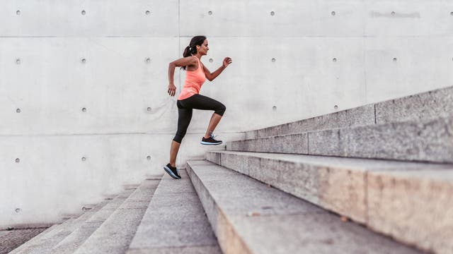 Eine Frau im Sportkleidung rennt draußen eine Treppe hinauf.
