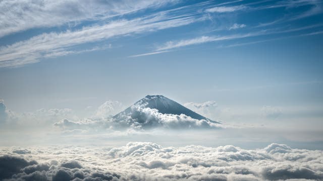 Fernluftaufnahme des Berges Fuji in Japan, der über den Wolken gipfelt.