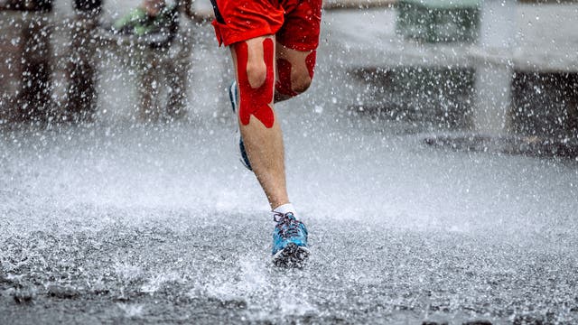 Ein Mann mit Kinesiotapes läuft durch den Regen