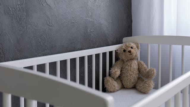Teddy sitzt in leerem Kinderbett