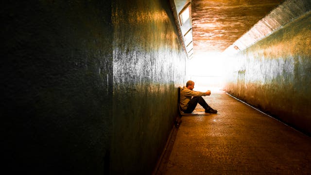 Ein Mann sitz in einem Tunnel und scheint nachzudenken.