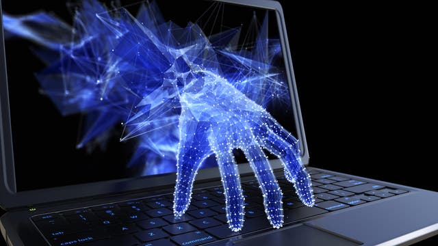 Digitale Hand in Blau greift aus einem Bildschirm auf den Laptop zu. Symbolisch für Cyberkriminalität und Datenraub.