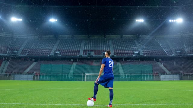 Ein Fußballer steht allein in einem leeren Stadion