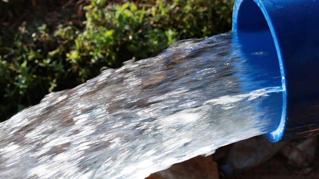 Wasser strömt aus der Öffnung eines blauen Rohrs.