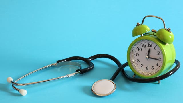 Ein Stethoskop und ein Wecker symbolisieren den Zusammenhang von Zeit und Medizin