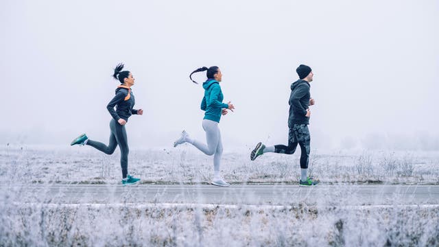Drei junge Leute joggen in winterlicher Landschaft