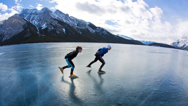 Zwei Schlittschuhläufer gleiten auf einem zugefrorenen See.