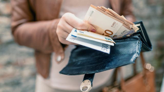 Eine Frau hält einen Geldbeutel mit Scheinen darin in der Hand