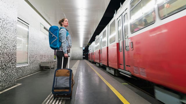 Ein Reisender wartet mit seinem Gepäck auf den Zug.